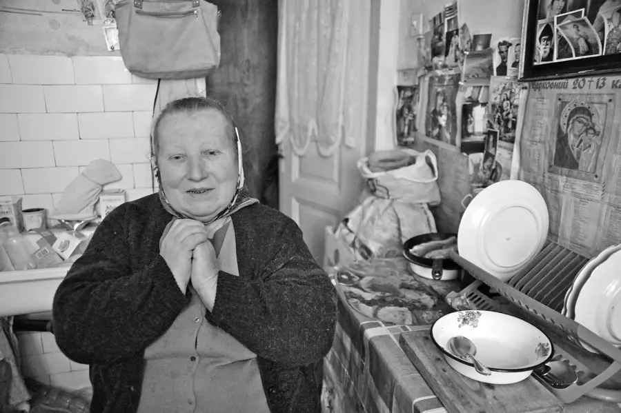 Alte Frau in ihrer Küche, die Hände gefaltet