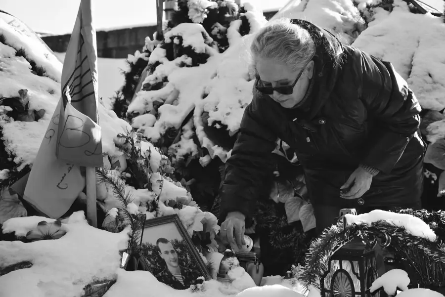 Frau pflegt ein Grab im Schnee